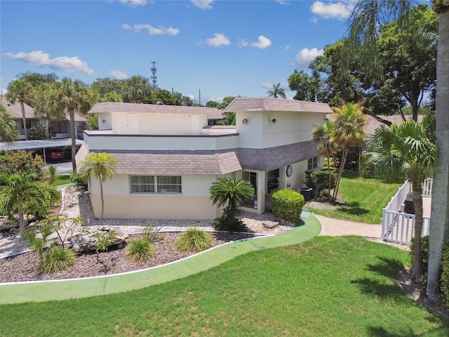 back of property with a lawn, fence, and stucco siding