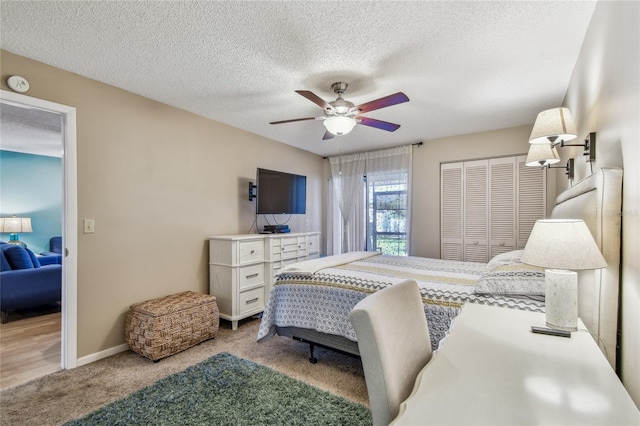 bedroom with baseboards, ceiling fan, a closet, a textured ceiling, and light colored carpet