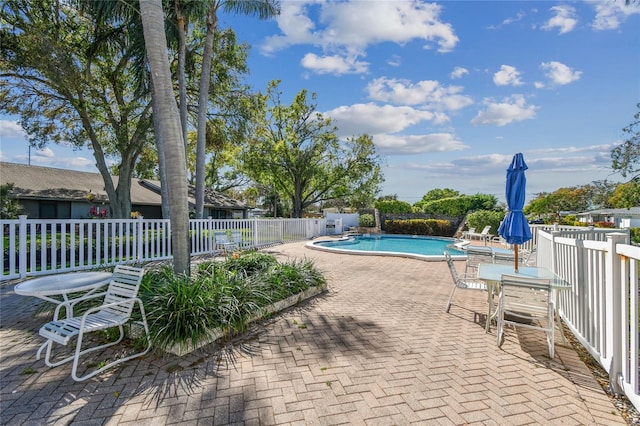 community pool with a patio and fence