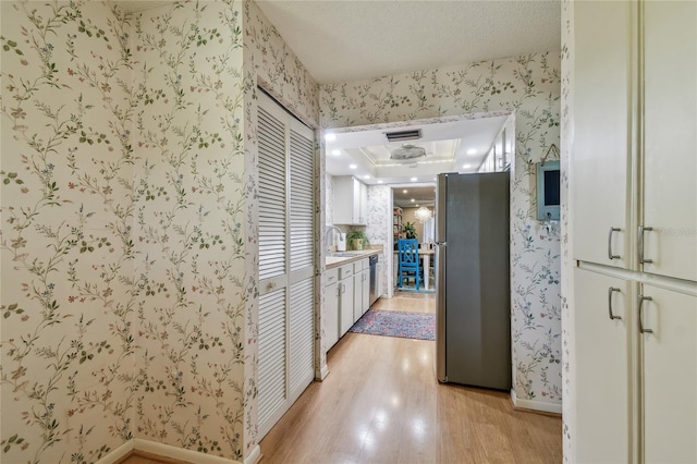 hallway with a sink, baseboards, light wood-style floors, and wallpapered walls