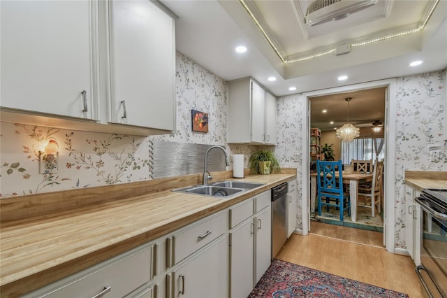 kitchen with wallpapered walls, light wood-style flooring, stainless steel appliances, and a sink