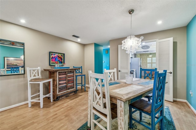 dining room with visible vents, baseboards, an inviting chandelier, wood finished floors, and a textured ceiling