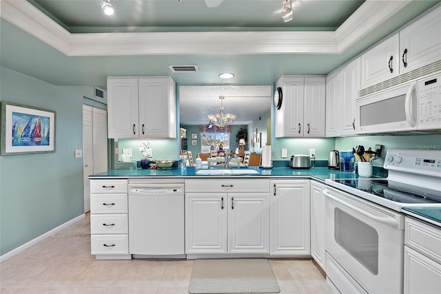 kitchen featuring dark countertops, white appliances, a raised ceiling, and a sink