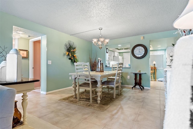 dining area with baseboards, a chandelier, a textured ceiling, and light tile patterned flooring