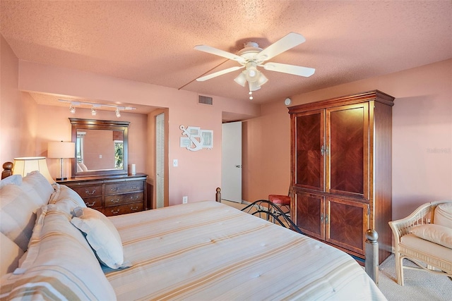 bedroom with a ceiling fan, visible vents, and a textured ceiling