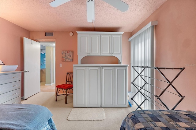 bedroom featuring a textured ceiling, a ceiling fan, visible vents, and light colored carpet