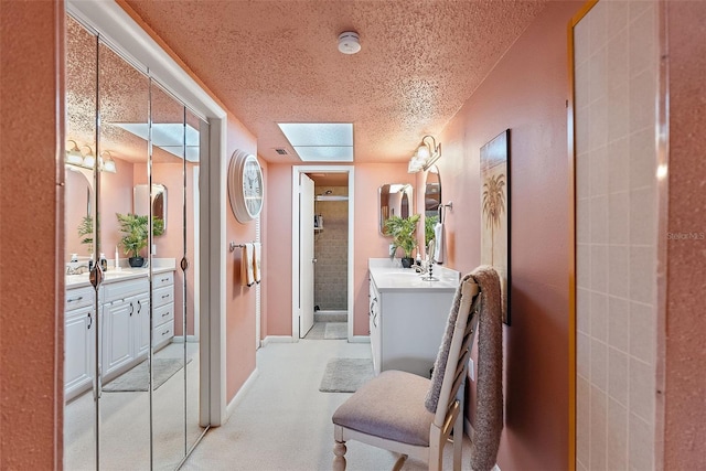 hall featuring light carpet, a textured ceiling, and baseboards