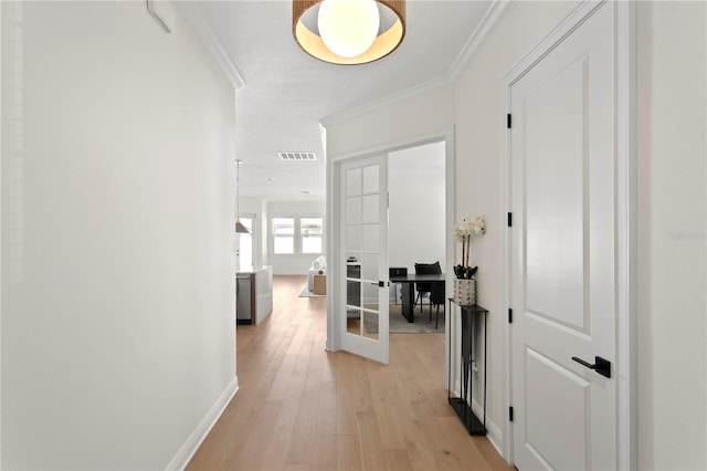 hallway featuring visible vents, baseboards, ornamental molding, french doors, and light wood-style floors