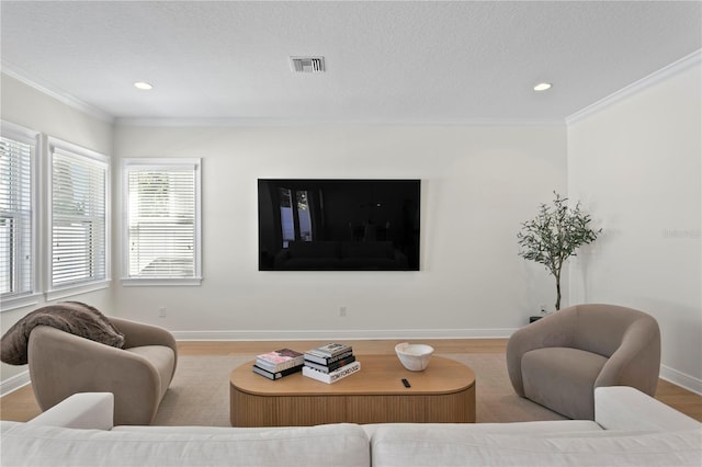 living room featuring visible vents, crown molding, baseboards, and wood finished floors