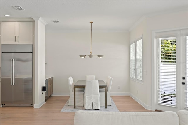 dining space with light wood-style flooring, visible vents, and ornamental molding