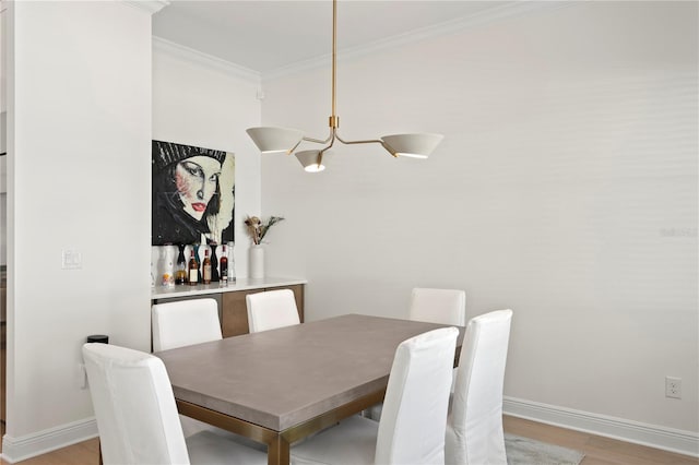 dining space with light wood-style flooring, ornamental molding, and baseboards