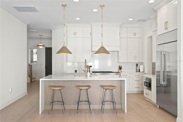 kitchen with built in fridge, light countertops, visible vents, and white cabinetry