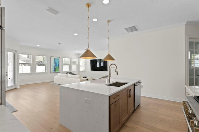 kitchen featuring a sink, visible vents, open floor plan, stainless steel dishwasher, and pendant lighting