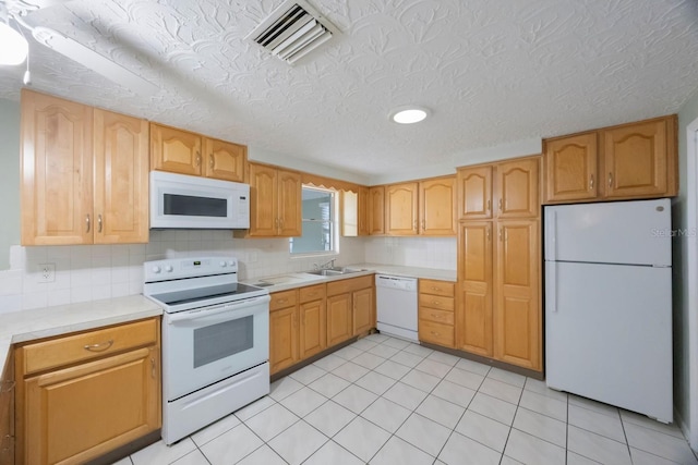 kitchen featuring tasteful backsplash, light countertops, visible vents, a sink, and white appliances