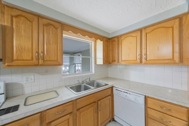 kitchen with a textured ceiling, white dishwasher, a sink, light countertops, and backsplash