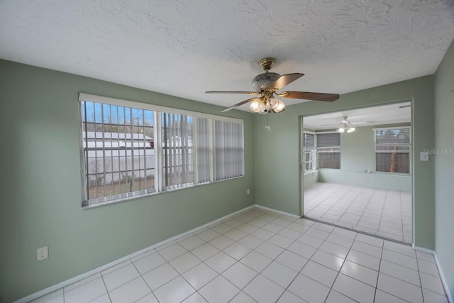 empty room featuring light tile patterned floors, baseboards, and a textured ceiling