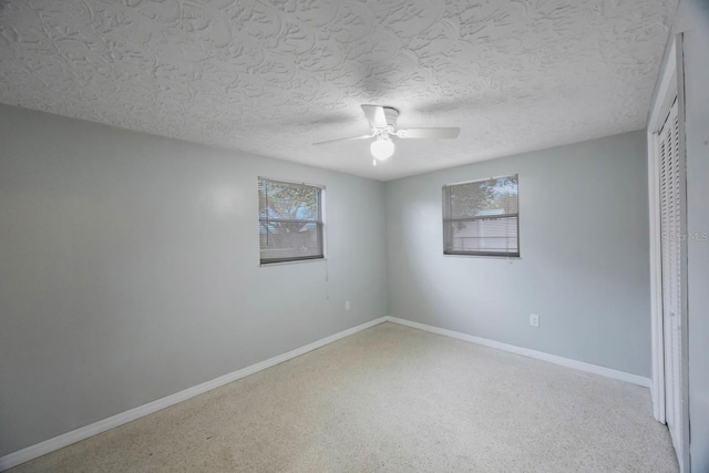 unfurnished bedroom with a textured ceiling, ceiling fan, a closet, and baseboards