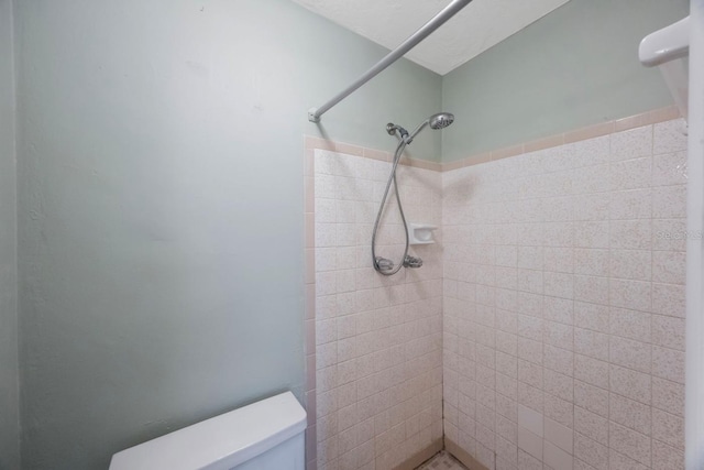 bathroom featuring tiled shower and toilet