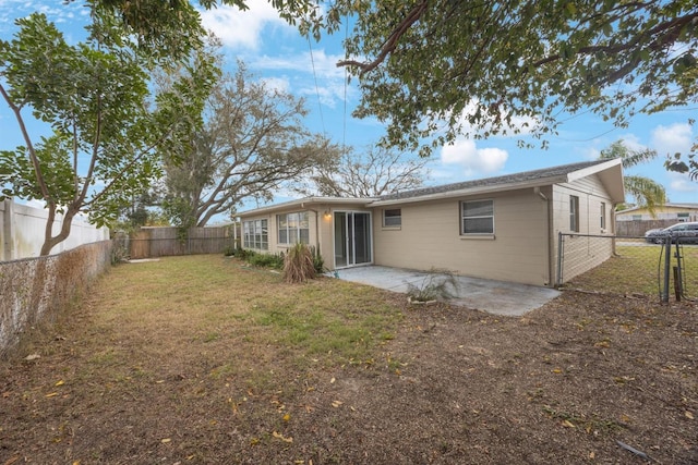 back of property with a fenced backyard, a lawn, and a patio