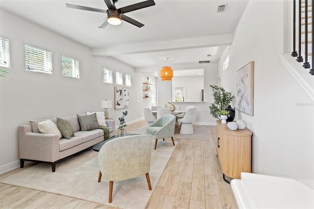 living room with light wood finished floors, baseboards, visible vents, ceiling fan, and beamed ceiling