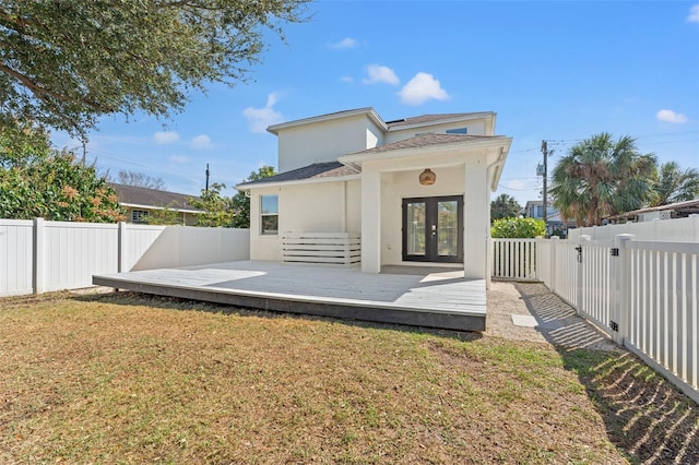 back of property featuring french doors, a yard, stucco siding, a fenced backyard, and a wooden deck