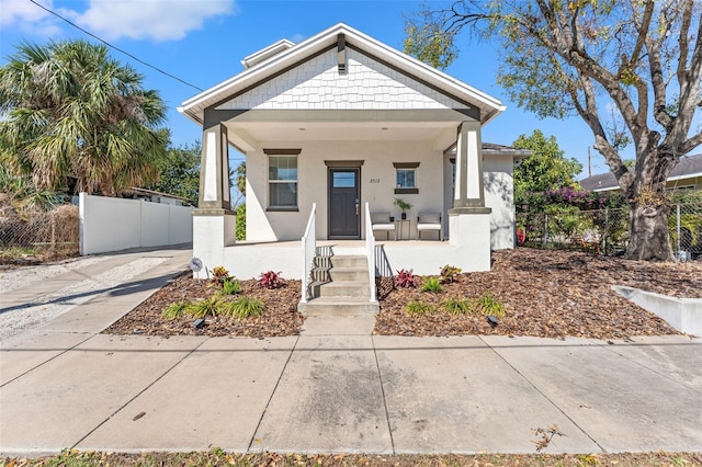 bungalow-style house with a fenced front yard, a porch, and stucco siding