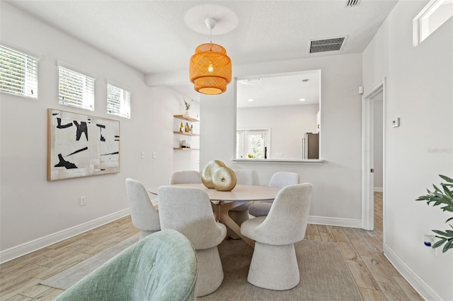 dining room with baseboards, visible vents, and light wood-style floors