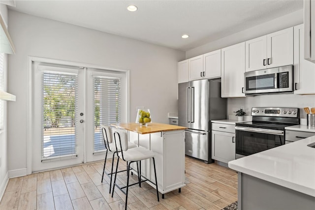 kitchen with stainless steel appliances, a breakfast bar area, a center island, and white cabinets