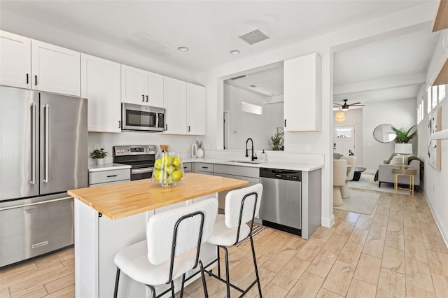 kitchen with a kitchen breakfast bar, appliances with stainless steel finishes, visible vents, and white cabinets