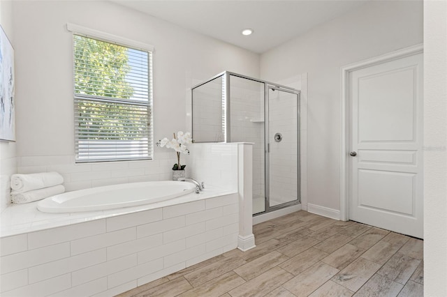 full bath featuring recessed lighting, a garden tub, a shower stall, and wood finished floors