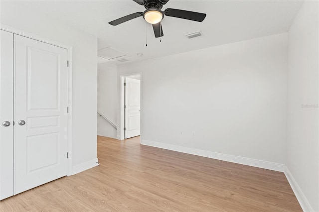 unfurnished room with light wood-style floors, attic access, visible vents, and baseboards