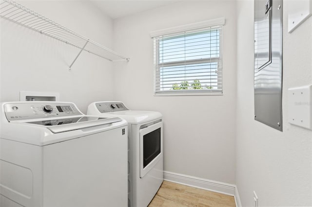 clothes washing area with laundry area, separate washer and dryer, light wood-type flooring, and baseboards