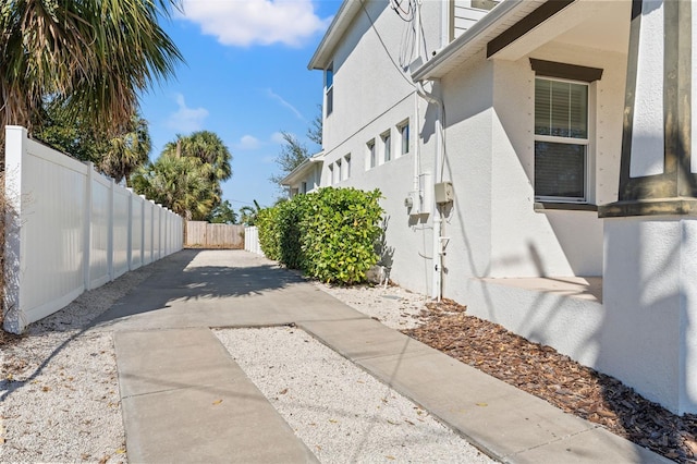 view of side of home with a fenced backyard and stucco siding