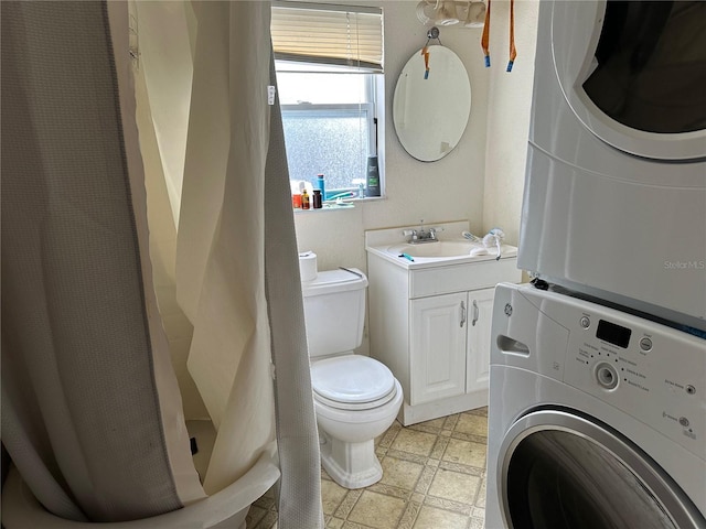 bathroom with stacked washing maching and dryer, vanity, toilet, and tile patterned floors