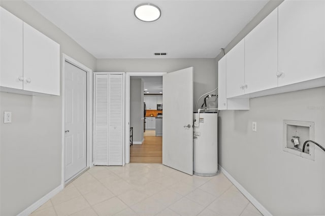 washroom with visible vents, baseboards, washer hookup, water heater, and cabinet space