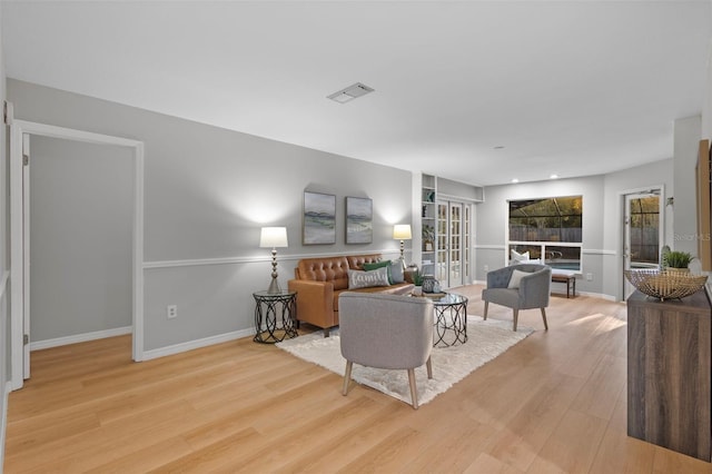 living room with visible vents, baseboards, and wood finished floors