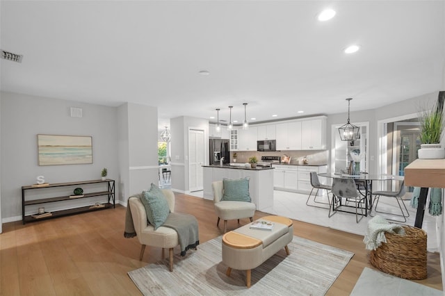 living area with baseboards, visible vents, recessed lighting, a notable chandelier, and light wood-type flooring