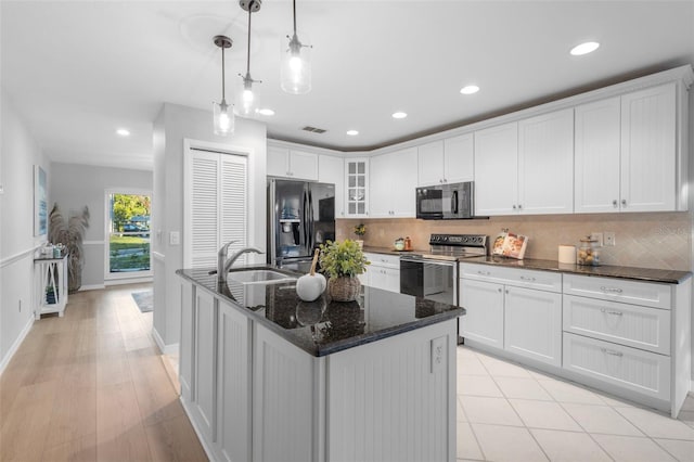 kitchen with tasteful backsplash, visible vents, white cabinets, and black appliances