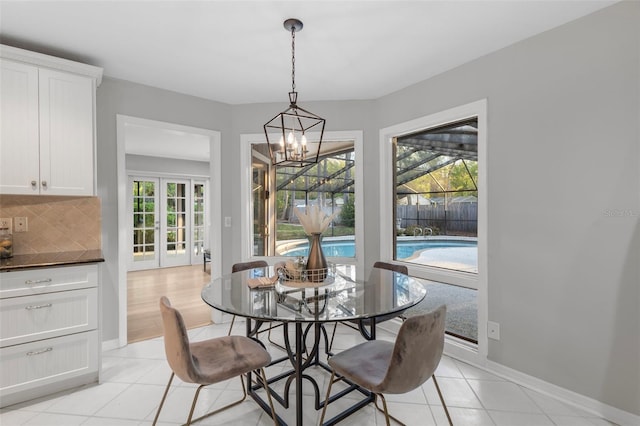 dining space featuring a notable chandelier, light tile patterned flooring, french doors, and baseboards