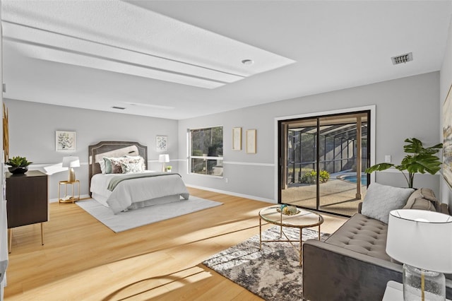 bedroom featuring access to exterior, multiple windows, wood finished floors, and visible vents