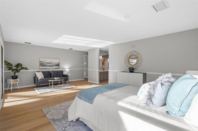 bedroom with light wood finished floors, visible vents, and baseboards