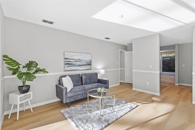 living area featuring wood finished floors, visible vents, and baseboards