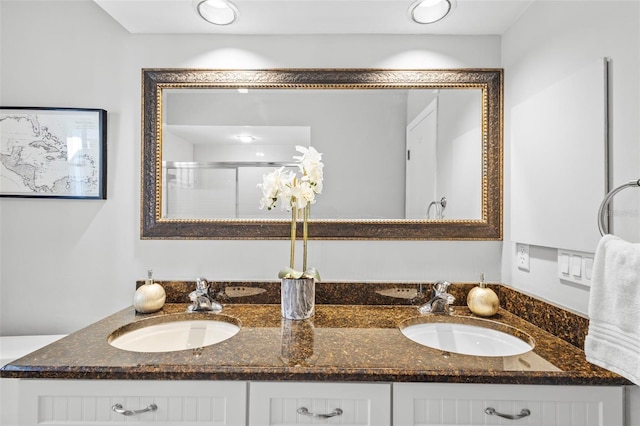 bathroom featuring double vanity, a stall shower, and a sink