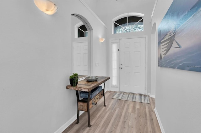 entryway with light wood-type flooring, baseboards, and arched walkways