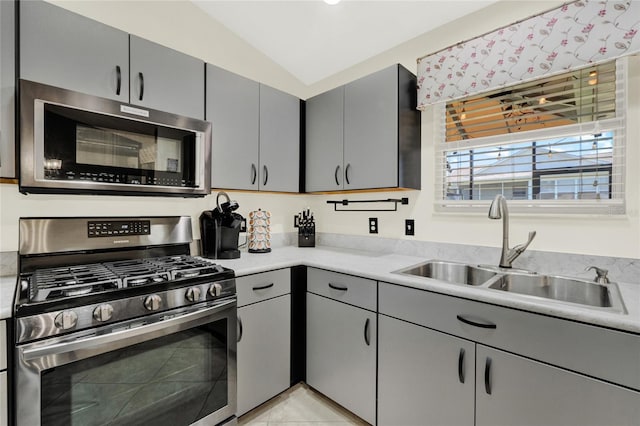 kitchen featuring stainless steel appliances, gray cabinets, light countertops, and a sink