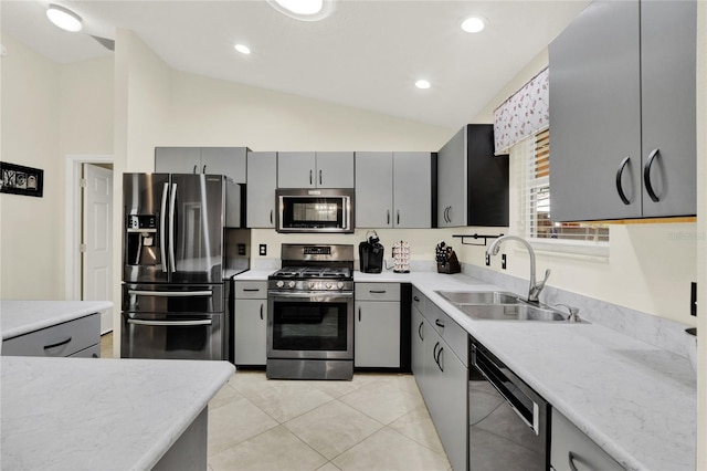 kitchen with lofted ceiling, appliances with stainless steel finishes, a sink, and gray cabinetry