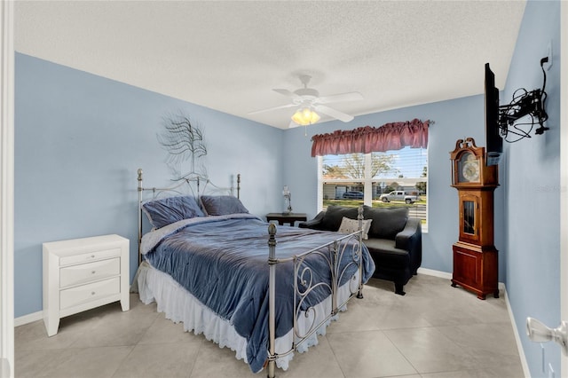 bedroom with ceiling fan, baseboards, a textured ceiling, and light tile patterned flooring