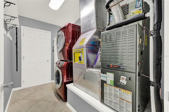 laundry room featuring heating unit, light tile patterned flooring, stacked washing maching and dryer, laundry area, and baseboards