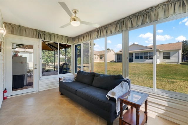 sunroom / solarium with a residential view and a ceiling fan