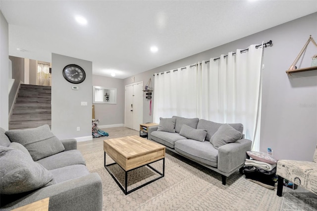 living room featuring light wood-style flooring, stairs, and baseboards